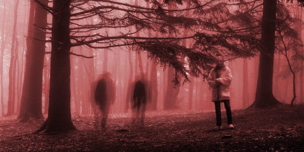 Two ghostly silouettes following a person in a forest